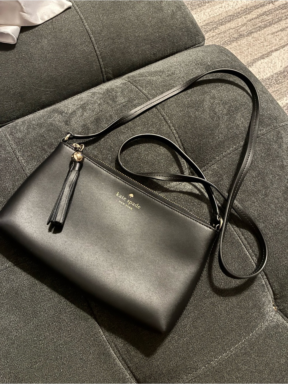 kate spade black leather crossbody with tassel and gold logo